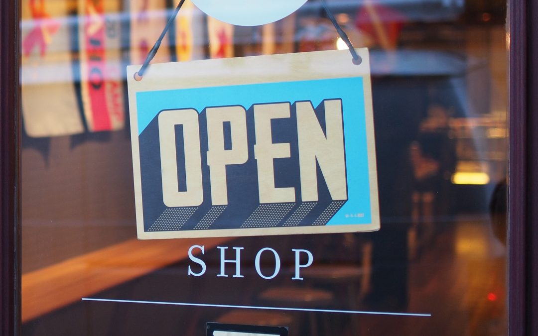 An open sign on a store that uses small business shipping.