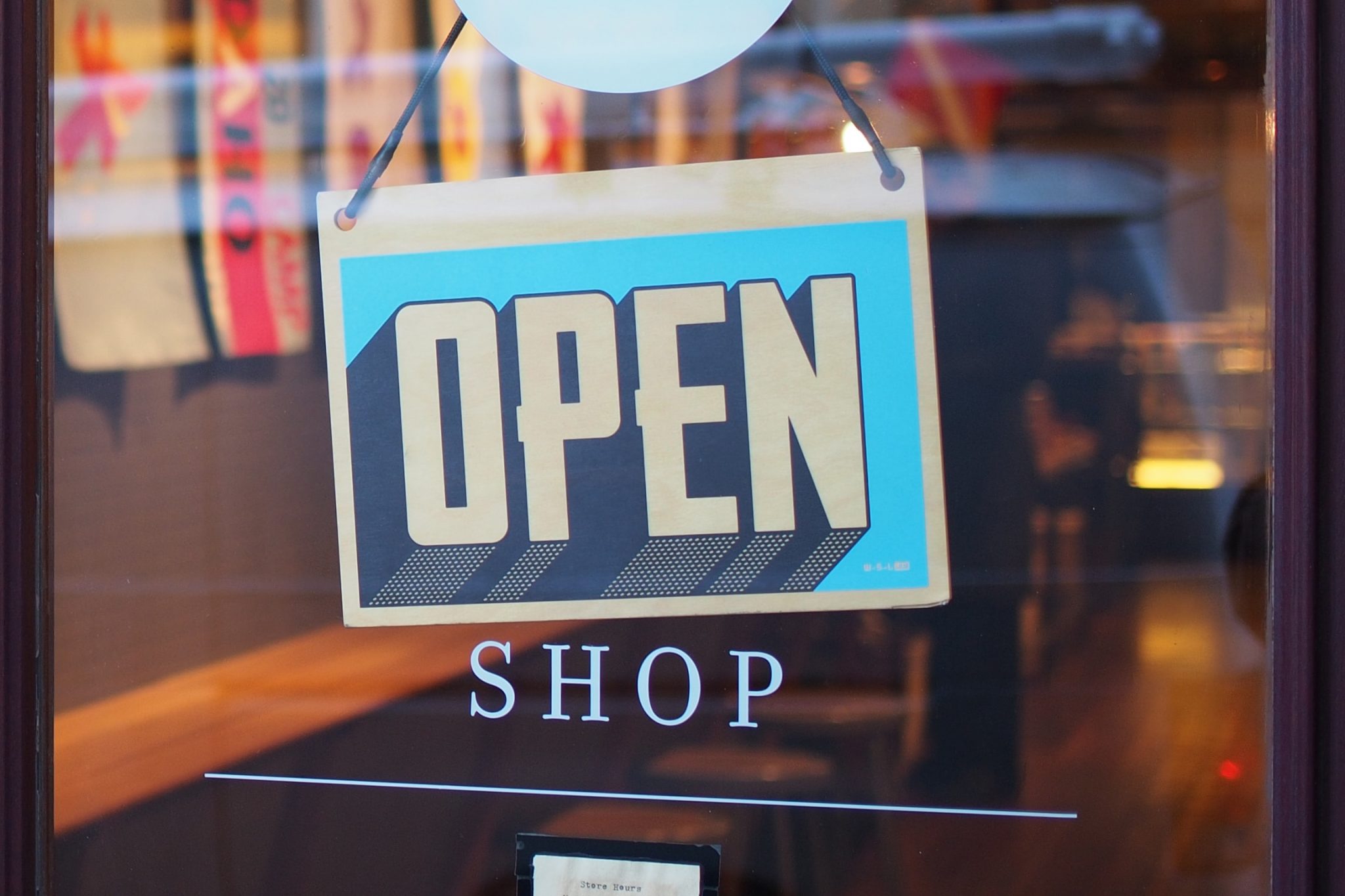 An open sign on a store that uses small business shipping.